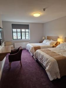 a bedroom with two beds and a desk and a window at Home Inn in Athlone