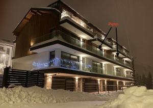 un edificio con la neve di fronte ad esso di notte di REST4U APARTAMENTY z SAUNAMI a Szczyrk