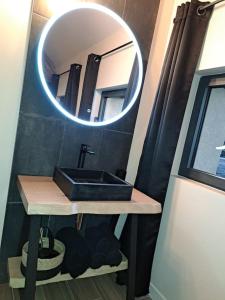 ein Bad mit einem Waschbecken und einem Spiegel in der Unterkunft La bergerie cosy - Sauna et bain nordique privatif in Saint-Denis-de-Jouhet