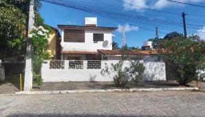 una casa blanca con una valla delante en Casa em Porto de Galinhas - PRIVÊ DAS ONDAS, en Porto de Galinhas