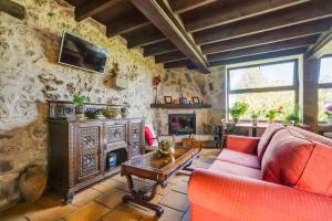 a living room with a red couch and a fireplace at Amaicha Hotel Rural in Ribadesella