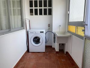 een kleine badkamer met een wasmachine en een wastafel bij Río, mar y montaña in Puentedeume
