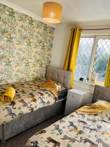 1 dormitorio con 2 camas individuales y papel pintado con motivos florales en Treetops - Sleeps 8 entire house private parking close to town centre and stadium, en Wigan