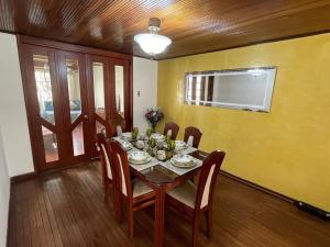 comedor con mesa, sillas y pared amarilla en Casa Linda, en Bogotá