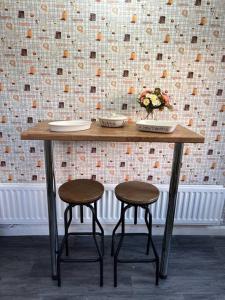 a wooden table with two stools in front of a wall at Treetops - Sleeps 8 entire house private parking close to town centre and stadium in Wigan