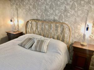 - un lit blanc avec 2 oreillers et du papier peint dans l'établissement La Chaumière de la Chaize, à Saint-Jouan-des-Guérets