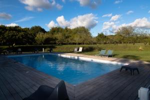 a swimming pool on a wooden deck with two chairs at LA CAVERIE DE PEYROUX A ORTHEVIELLE (40300) in Orthevielle
