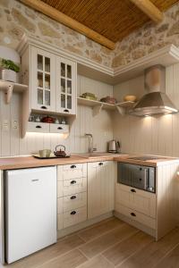a kitchen with white cabinets and a white refrigerator at Physis Country House 2 near Matala beach & Faistos in Kousés