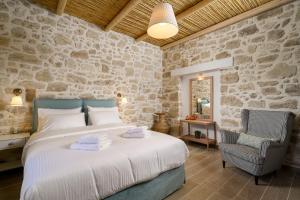 a bedroom with a bed and a stone wall at Physis Country House 2 near Matala beach & Faistos in Kousés