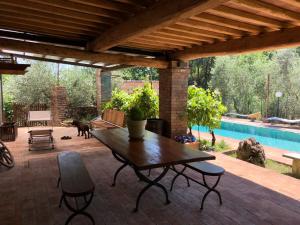 a patio with a wooden table and a pool at Agriturismo San Giusto in Sovicille