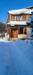 een huis met een sneeuwbedekte tuin ervoor bij Arnika Tatariv in Tatariv