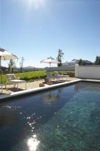 a swimming pool with two chairs and umbrellas at Hawksmoor House in Stellenbosch
