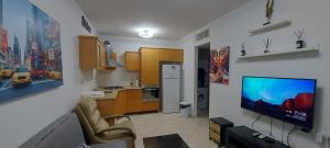 a living room with a kitchen and a tv on a wall at Apartment Amdar Village עם ממ"ד in Eilat