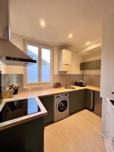 uma cozinha com armários verdes e uma máquina de lavar e secar roupa em Casa Paris - Paisible & Central T2 - Coeur de Brive - 4 Personnes em Brive-la-Gaillarde