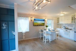 eine Küche mit weißen Schränken und einem Tisch mit Stühlen in der Unterkunft CICHAta Nad Zatoką in Cammin in Pommern