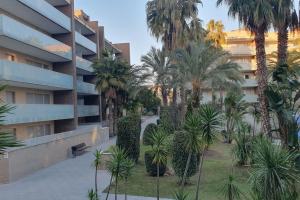 an apartment complex with palm trees in front of a building at Eden Flat Port Aventura in Salou