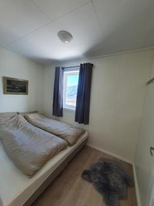 um pequeno quarto com uma cama e uma janela em Molden 2-fjellutsikt og jacuzzi tilgang. em Luster