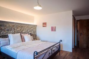 1 dormitorio con 1 cama grande y pared de piedra en Aux Trois Soleils, en Chexbres