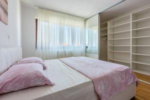 um quarto com uma cama grande e lençóis cor-de-rosa em Ga Lu em Novi Vinodolski