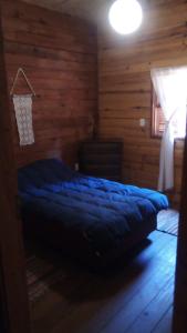 1 dormitorio con 1 cama en una cabaña de madera en Cabaña en el bosque de punta del diablo, en Punta del Diablo