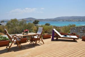 una terraza de madera con mesa, sillas y agua en Kolymbithres Seaside Villa, en Kolympithres