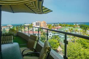 einen Balkon mit 2 Stühlen und einem Sonnenschirm in der Unterkunft The Zanakri homes Oceanfront in Mombasa