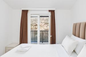a bedroom with a white bed and a window at Apartments Rozer in Kotor