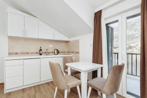 a kitchen with white cabinets and a table and chairs at Apartments Rozer in Kotor