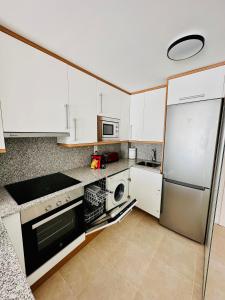 een keuken met witte kasten en een roestvrijstalen koelkast bij Apartamento con Piscina y Jardín Espectacular Cala Sirenas - Nuevo in Miami Platja