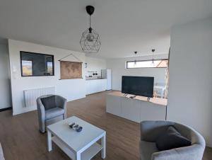 uma sala de estar com duas cadeiras e uma mesa e uma televisão em Bel appartement 75m2 em Mirefleurs