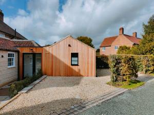 a timber clad house with a driveway at The Larch Room in Brandsby