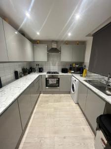 a kitchen with white cabinets and a washer and sink at Archway Apartment in London