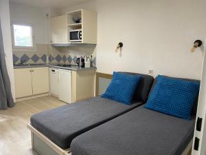 1 dormitorio con 1 cama con almohadas azules y cocina en Domaine Valescure vue Piscine ou Pinede - Wifi en Saint-Raphaël