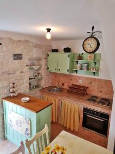 a kitchen with green cabinets and a clock on the wall at Vintage stone house ELDO in Podaspilje, Omiš in Omiš