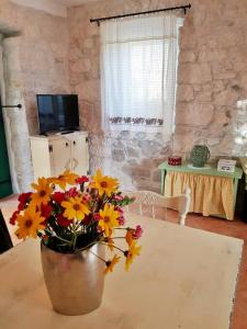 eine Vase mit Blumen auf einem Tisch in einem Zimmer in der Unterkunft Vintage stone house ELDO in Podaspilje, Omiš in Omiš