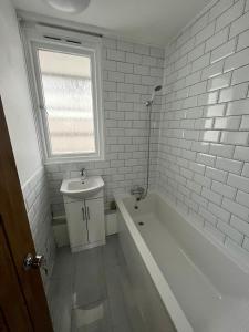 a bathroom with a tub and a sink and a window at Archway Apartment in London