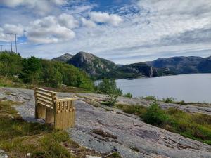 un banco de madera sentado en una colina con vistas a un lago en Holiday Apartment in Flatanger en Vik