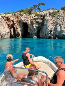 a group of people on a boat in front of a cave at To Votsalo in Karpathos