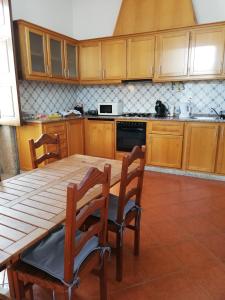 a kitchen with wooden cabinets and a wooden table and chairs at casa cardeal saraiva in Ponte de Lima