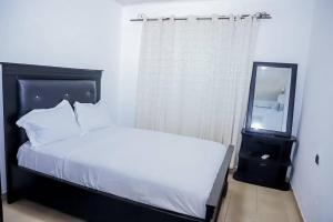 een slaapkamer met een wit bed en een spiegel bij Ocean Breeze in Limbe