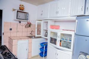 a kitchen with white cabinets and a blue refrigerator at Ocean Breeze in Limbe
