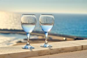 two wine glasses sitting on a ledge near the ocean at Village Center - Ocean View in Ericeira