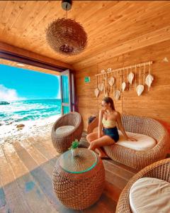 Hotel Prana Beach في بارو: امرأة تجلس على سرير في غرفة مطلة على المحيط