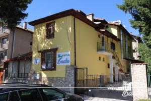 a yellow house with a car parked in front of it at ВИЛА БАЕВИ in Velingrad