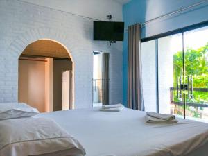 1 dormitorio con 1 cama blanca grande y ventana en Pousada Boa Sorte en Cumuruxatiba