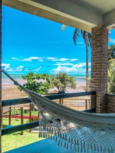 een hangmat op een veranda met uitzicht op de oceaan bij Pousada Boa Sorte in Cumuruxatiba