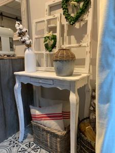 a white console table with a mirror and baskets at Une Histoire de Loup in Stembert