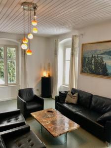 a living room with a black couch and a table at Secret Garden Villa in Pörtschach am Wörthersee