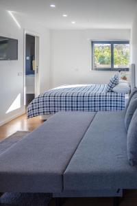 1 dormitorio con cama, sofá y ventana en Cork House, en Vila Praia de Âncora