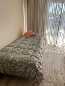 - un lit avec une couette grise dans une chambre dotée d'une fenêtre dans l'établissement Departamento Tierras del Malbec, à San Rafael